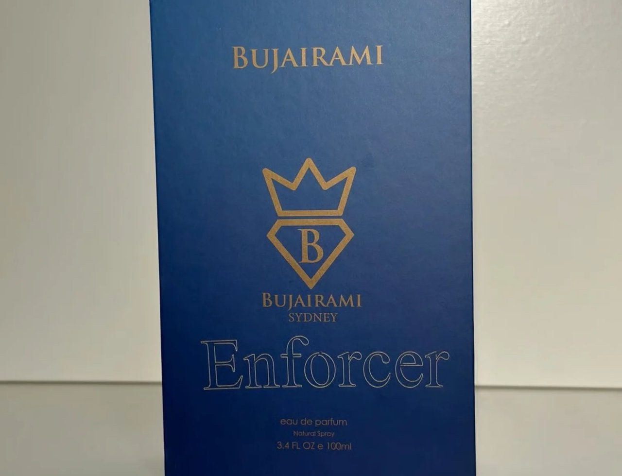 Bujairami Enforcer oleh Bujairami Eau de Parfum 100ml — Kotak biru dengan logo mahkota emas dan tulisan, memaparkan nama produk 'Enforcer' dalam huruf emas besar.