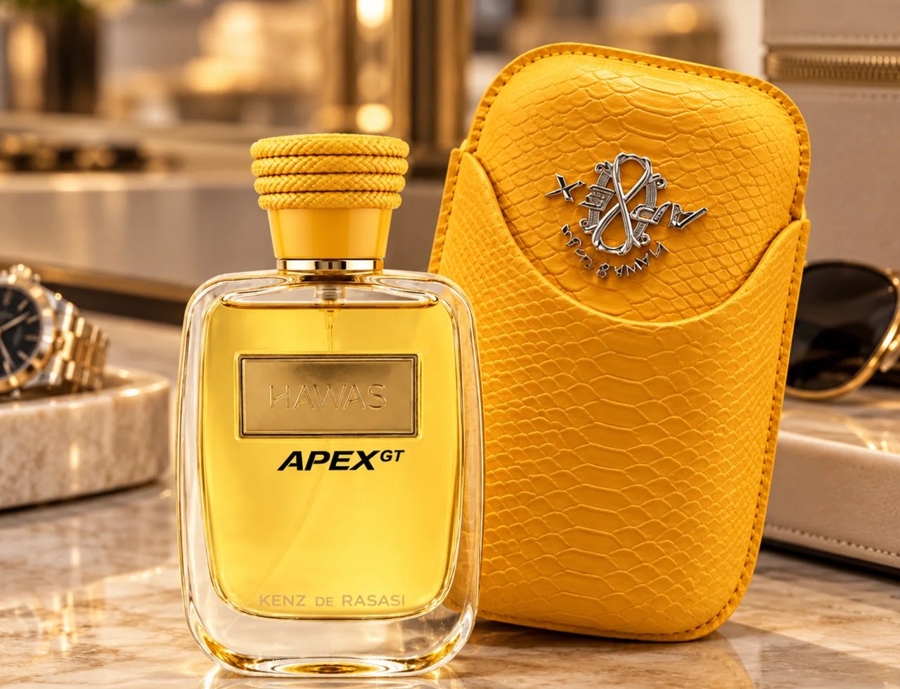Kenz de Rasasi Hawas Apex GT — Yellow textured case with silver emblem next to a clear glass perfume bottle with gold cap and label, on a marble surface.