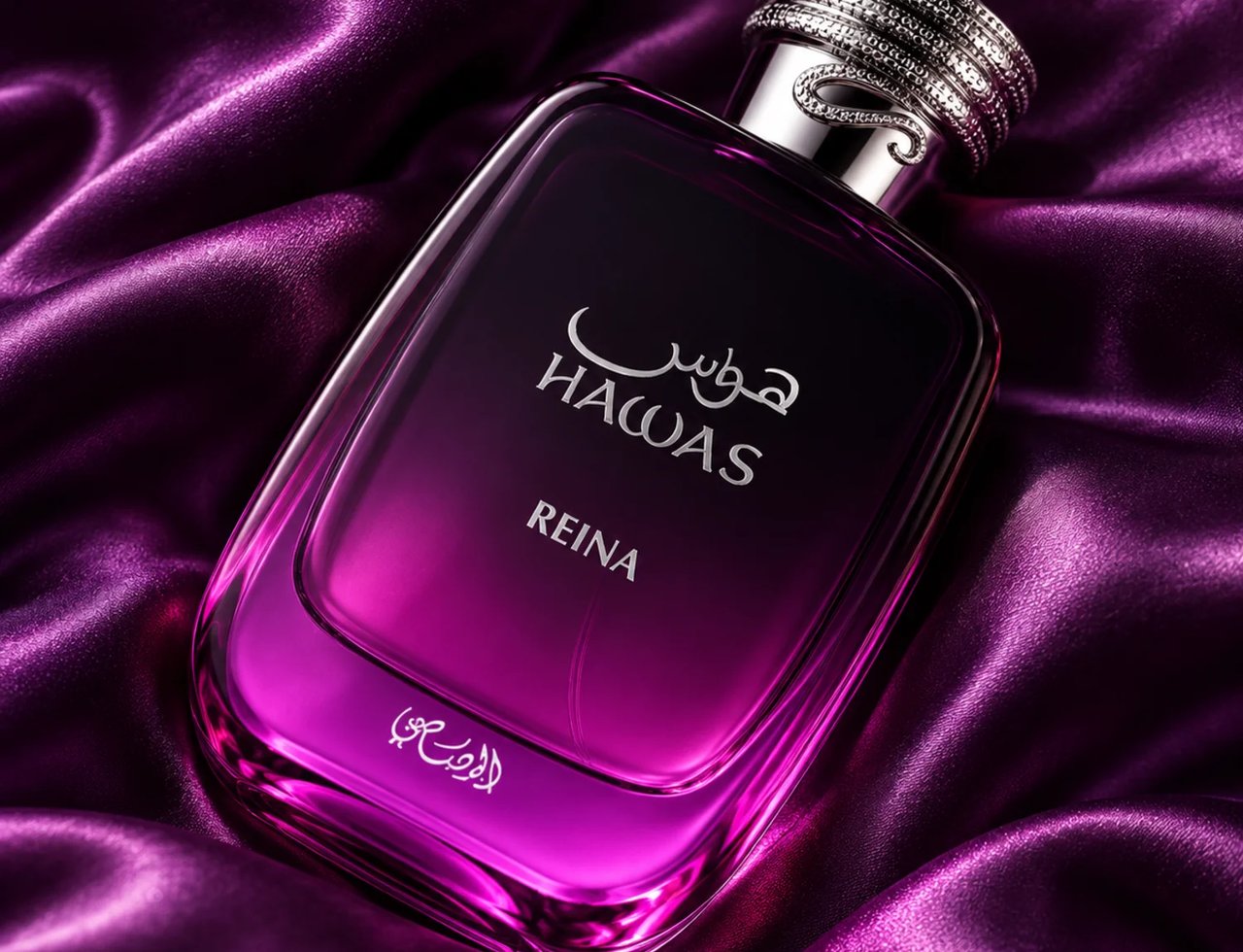 RASASI Hawas Reina by Rasasi 100ml EDP — Botol minyak wangi kaca segi empat dengan kemasan ungu ke jernih, diletakkan di atas fabrik satin ungu berlipat. Botol mempunyai tulisan perak Bahasa Arab dan Inggeris, serta penutup perak berhias.