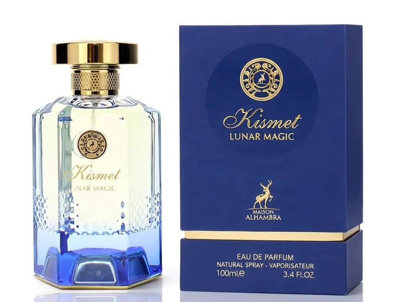 Maison Alhambra Kismet Lunar Magic 100ml — A clear glass perfume bottle with a gold cap and blue gradient base, next to its matching blue and gold box, both featuring gold circular emblems and deer motifs. | Maison Alhambra Kismet Lunar Magic 100ml — Botol minyak wangi kaca jernih dengan penutup emas dan tapak gradien