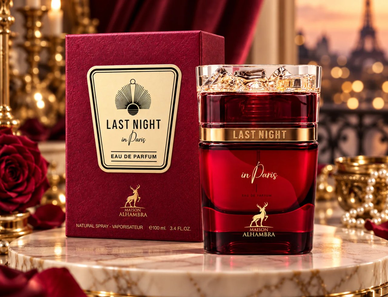Maison Alhambra Last Night in Paris — Red glass perfume bottle and matching box on a marble surface, with a blurred Parisian cityscape and red roses in the background.