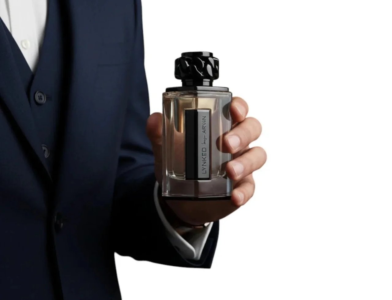 Afnan Lynked Freedom by Afnan 100ml Eau De Parfum — Man in a navy suit holding a clear glass perfume bottle with a black cap and a dark liquid inside.
