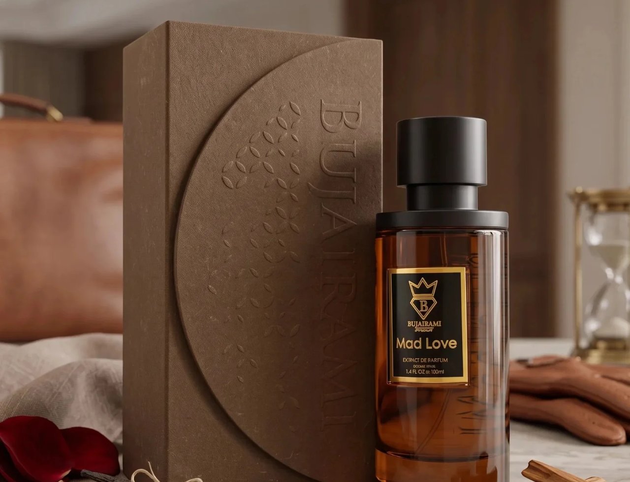 Bujairami Mad Love 100ml Extrait Unisex — Botol minyak wangi kaca coklat bertutup hitam dan label emas, bersebelahan kotak tekstur coklat sepadan. Kelopak mawar, kacang vanila, dan serpihan kayu disusun di sekeliling botol dan kotak di atas permukaan marmar.