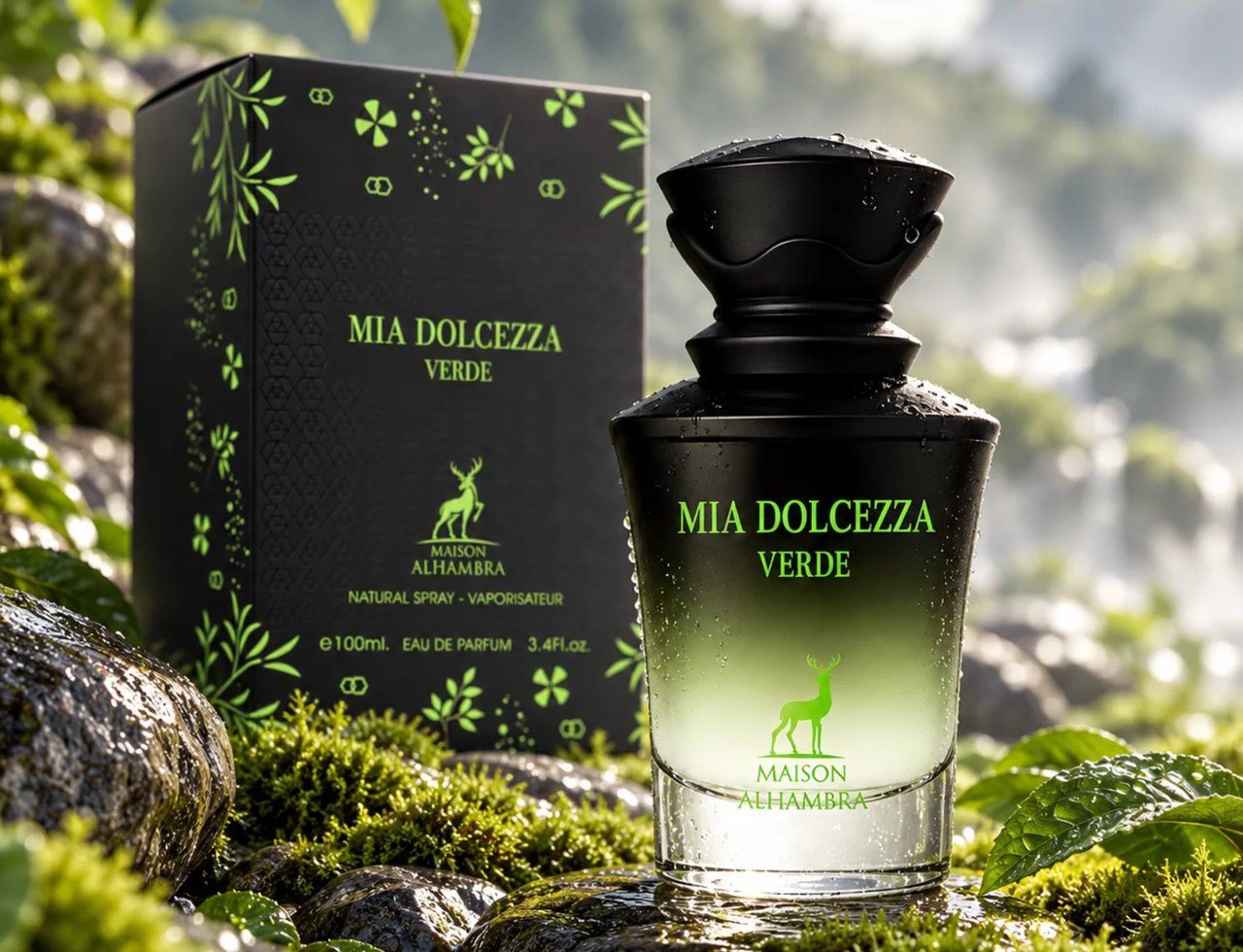 Maison Alhambra Mia Dolcezza Verde EDP Unisex — Botol minyak wangi hitam dengan gradien hijau dan titisan air, bersebelahan kotak hitamnya, diletakkan di atas batu berlumut dengan latar belakang air terjun yang kabur.
