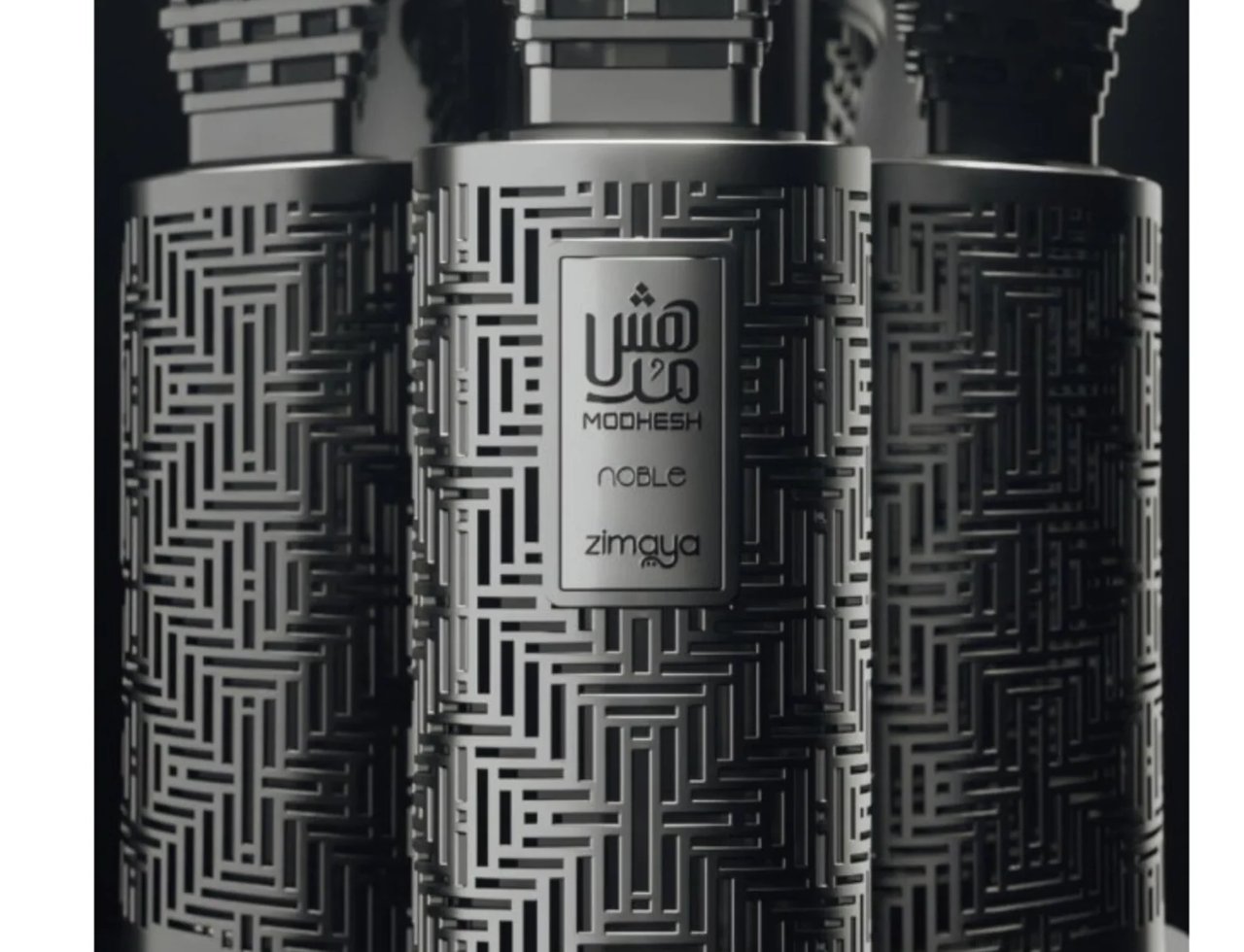Zimaya Modhesh Noble 100ml — Tiga botol wangian Zimaya Modhesh Noble berlatar belakang gelap, menampilkan reka bentuk ukiran geometrik yang rumit pada badan botol.