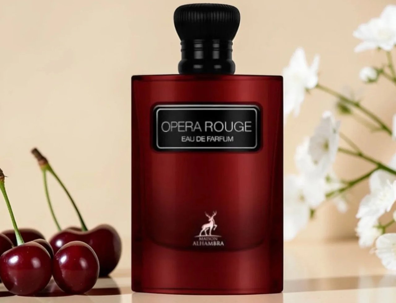 Maison Alhambra Opera Rouge by Maison Alhambra for Women 100ml — Botol wangian merah berkilat dengan penutup hitam, label "OPERA ROUGE EAU DE PARFUM" dan logo rusa di bahagian bawah, dihiasi dengan buah ceri merah dan bunga putih di latar belakang
