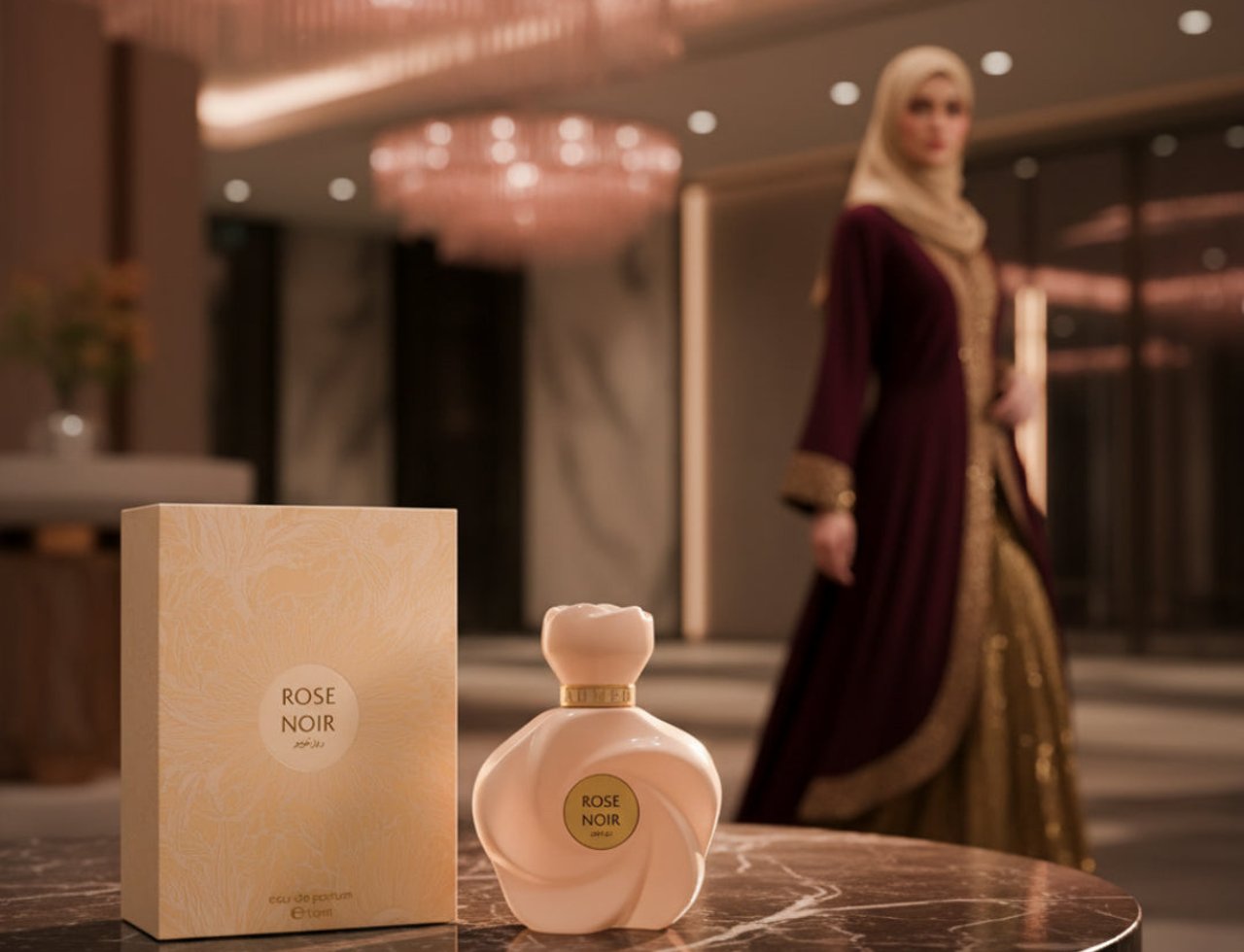 Ahmed Al Maghribi Rose Noir by Ahmed Al Maghribi EDP Women — Kotak wangian dan botol Rose Noir di atas meja marmar, dengan wanita berhijab memakai jubah di latar belakang.