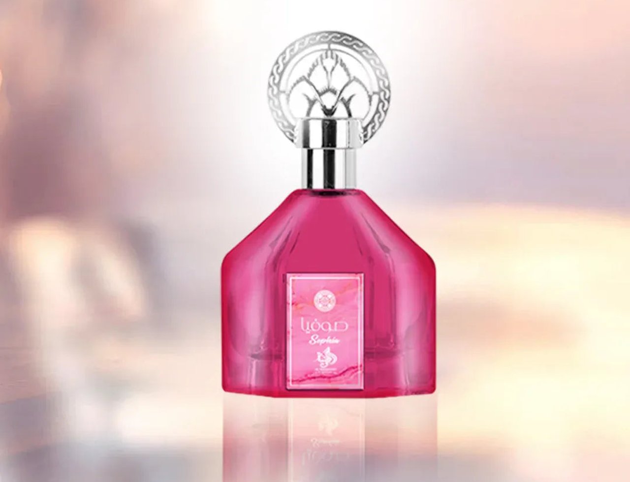 Al Wataniah Sophia – Pink glass perfume bottle with ornate silver cap, centered on a soft, blurred pink and white background