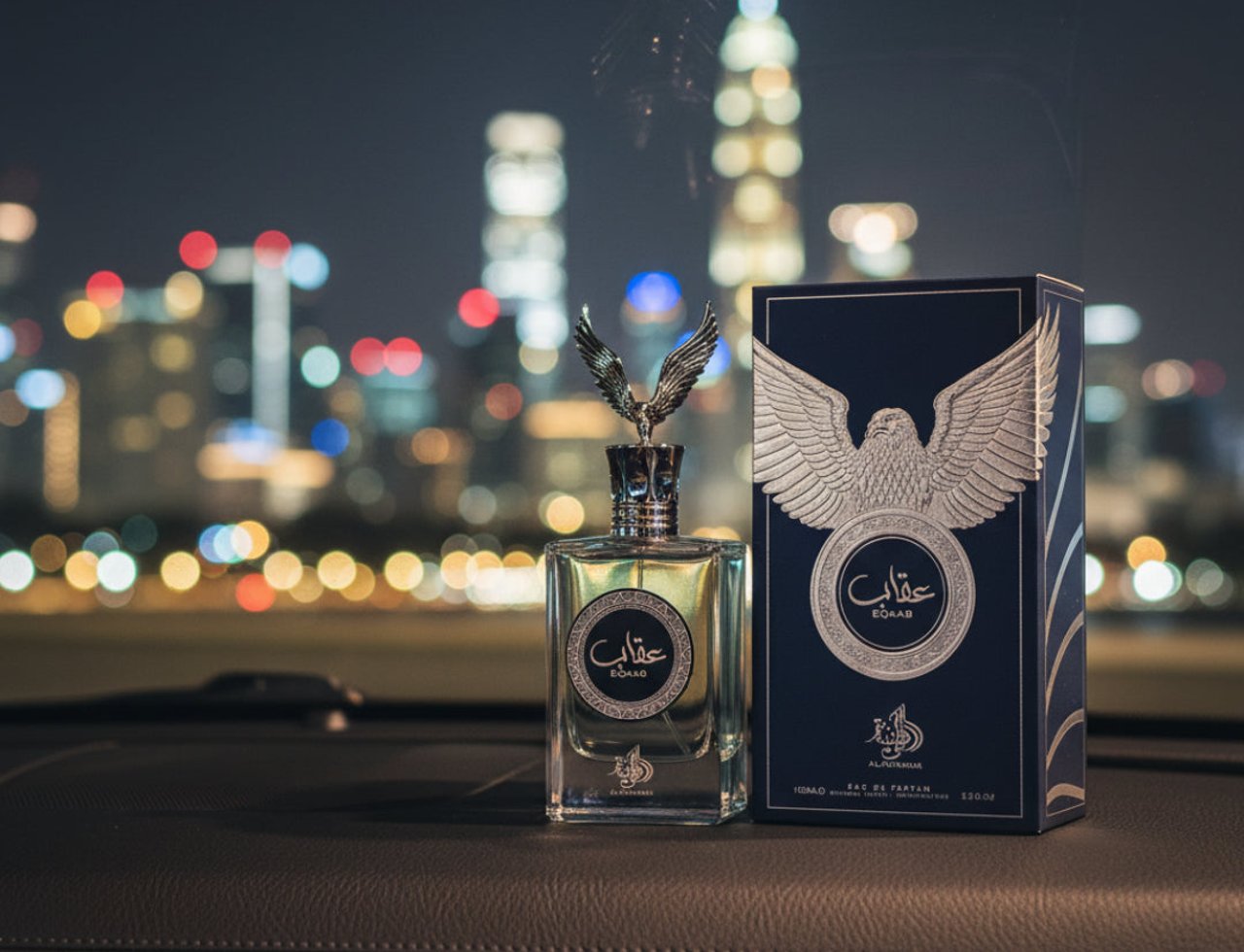 Al Wataniah Eqaab by Al Wataniah Elite 100 ml for Men — Botol wangian kaca jernih dengan penutup emas berbentuk helang, diletakkan di atas papan pemuka kereta gelap, dengan latar belakang bandar malam yang terang.