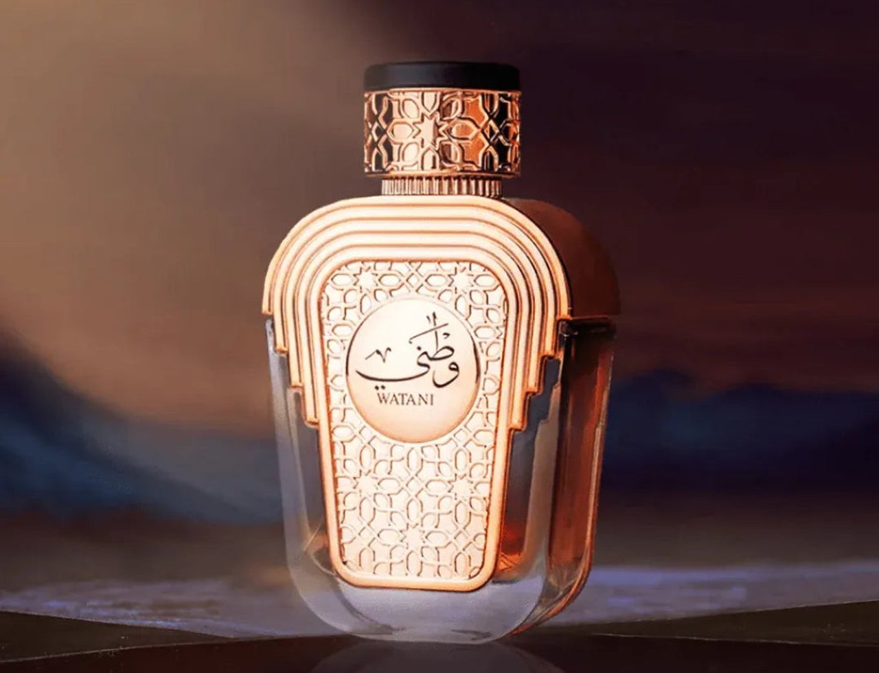 Al Wataniah Watani 100ml EDP – Ornate gold bottle with Arabic script and black cap, set against a blurred landscape