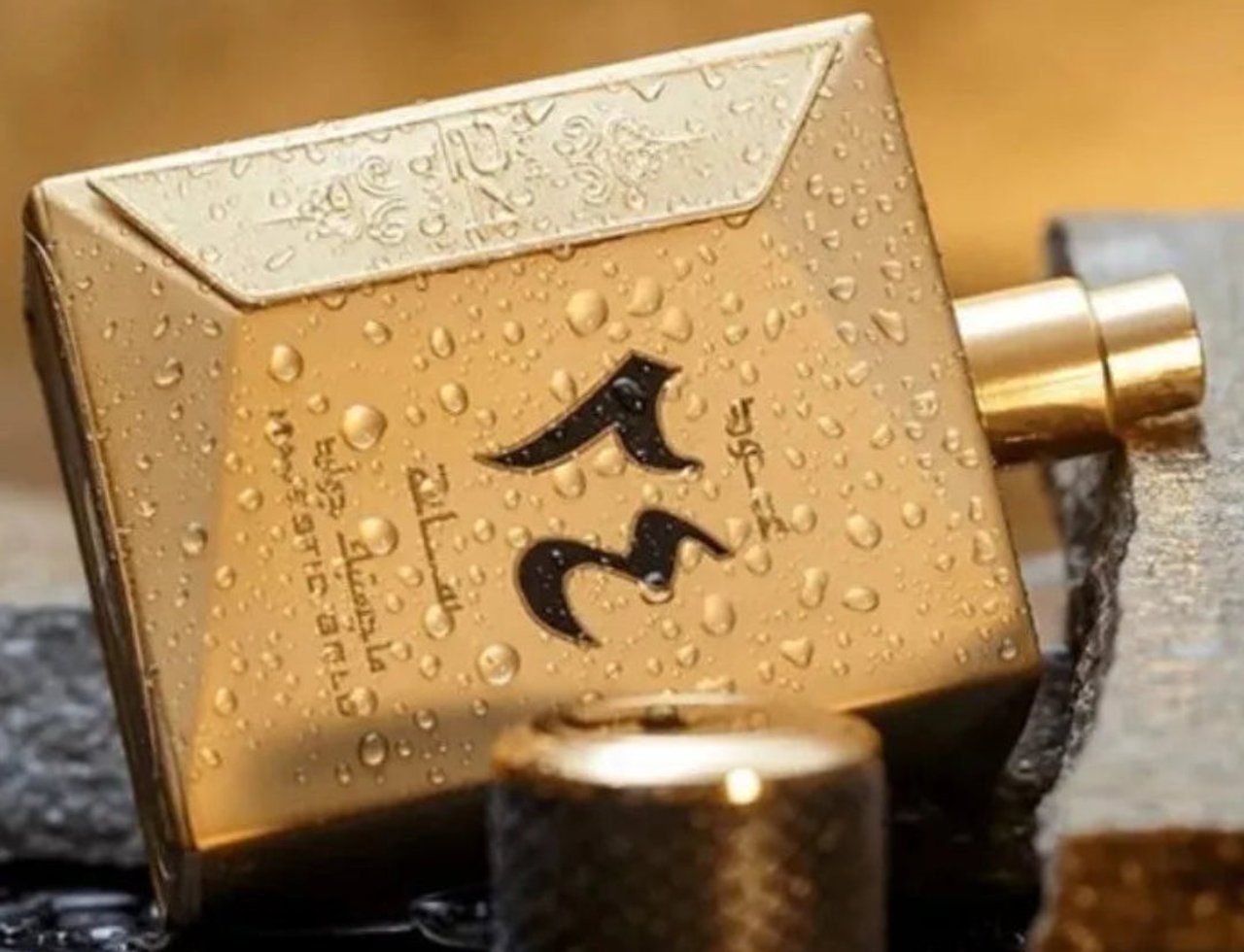 Ard Al Zaafaran Oud 24 Hours Majestic 100ml EDP Man — Gold perfume bottle with water droplets, resting on dark stones.