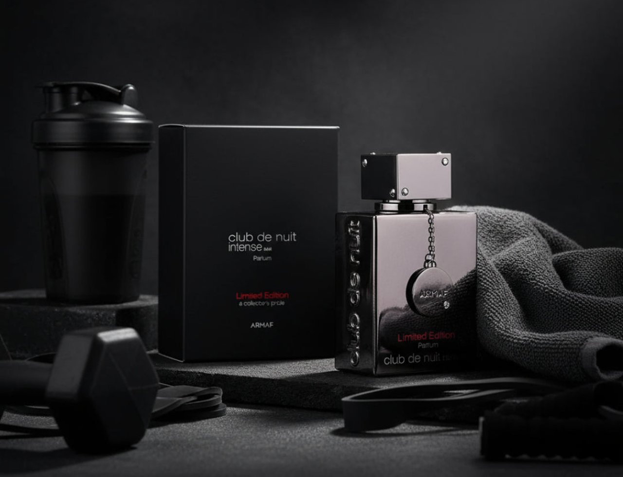 Armaf Club De Nuit Intense Limited by Armaf 105ml EDP Men CDNI — Set kelengkapan minyak wangi dengan kotak hitam, botol berkilat, penutup kelabu, dan aksesori gimnasium seperti shaker dan dumbbell di latar belakang gelap.