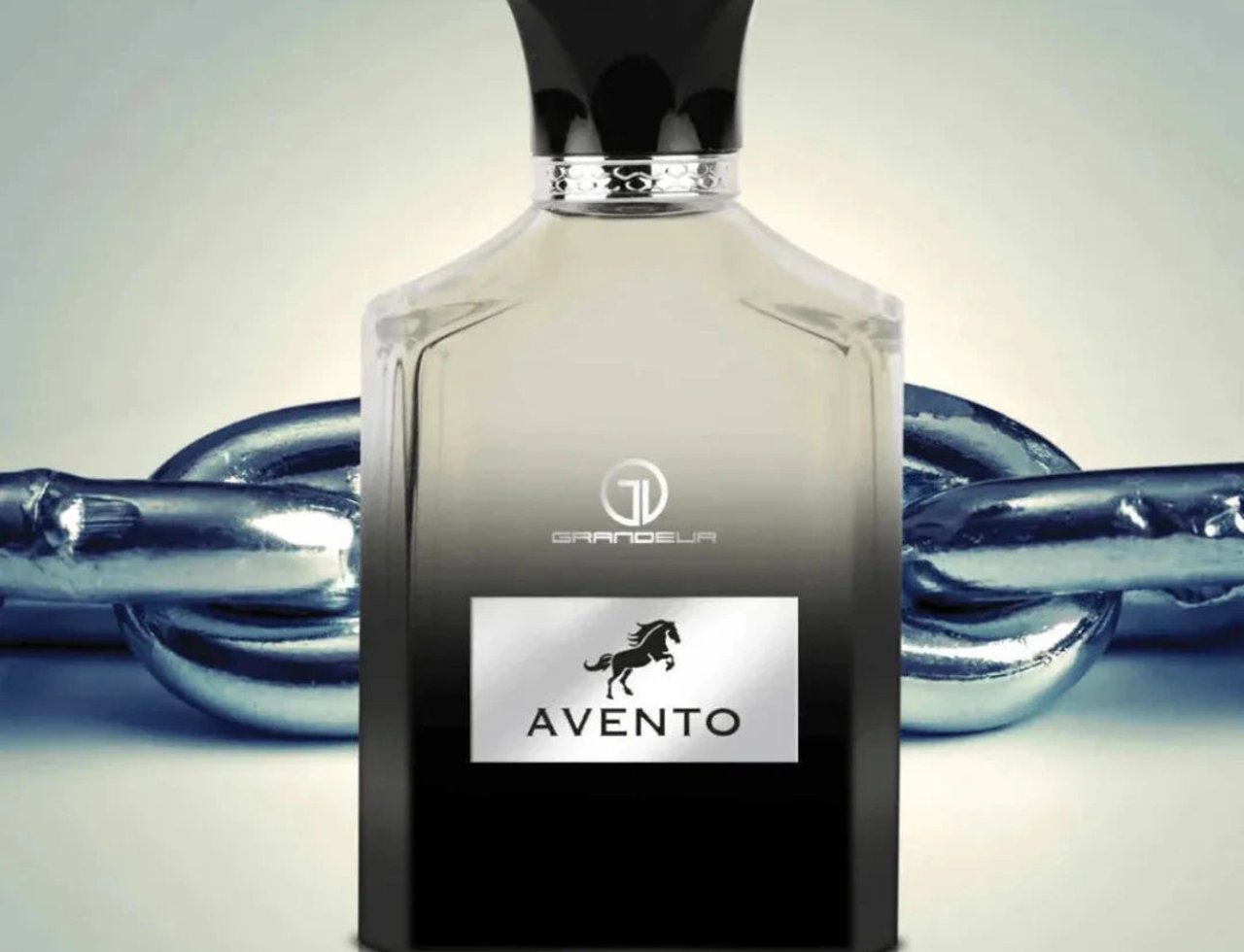 Grandeur Avento Perfume Man 100ml EDP Grandeur — A clear glass perfume bottle with a black cap and silver accents, featuring a black label with a horse silhouette and the text 'AVENTO' and 'GRANDEUR', set against a background of metallic chain links.