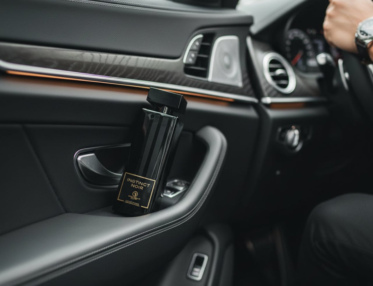 Grandeur Instinct Noir by Grandeur 100ml For Men — Black perfume bottle with gold label resting on the leather door panel of a luxury car.