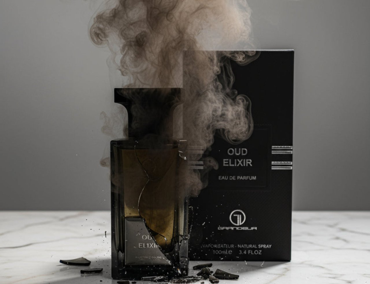 Grandeur Oud Elixir oleh Grandeur Elite – Botol minyak wangi kaca retak berisi cecair gelap, dikelilingi serpihan kaca pecah dan asap gelap, dengan kotak produk di latar belakang.