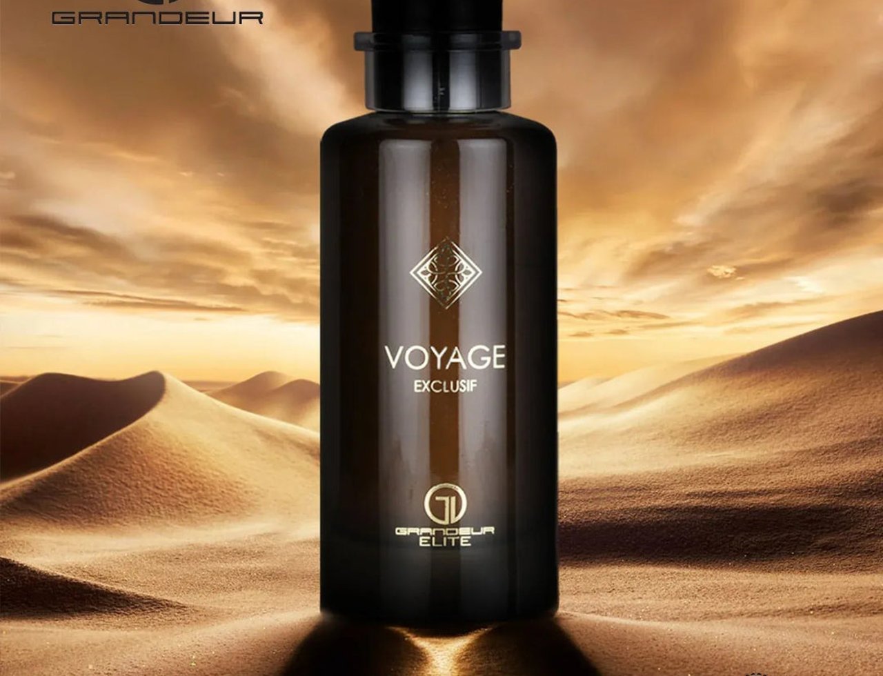 Grandeur Voyage Exclusif by Grandeur Elite — Dark glass perfume bottle with black cap, set against a desert landscape with sand dunes and a dramatic sky.