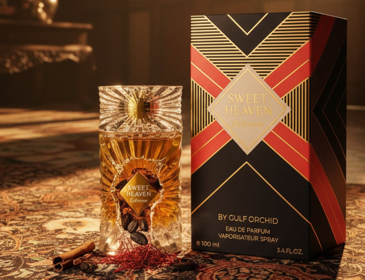 Gulf Orchid Sweet Heaven Extreme by Gulf Orchid 100ml Unisex — Botol minyak wangi kaca jernih beraksen emas reka bentuk pancaran matahari, bersebelahan kotak corak hitam emasnya, diletakkan di atas permaidani bermotif dengan benang kunyit dan batang kayu manis.
