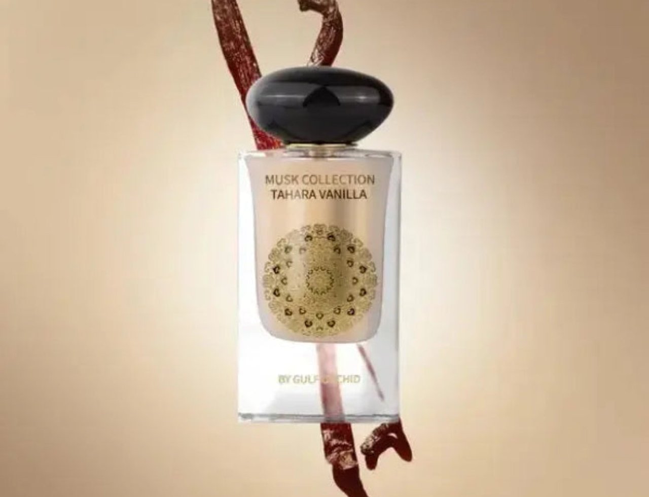 Gulf Orchid Musk Tahara Vanilla 60ml Gulf Orchid Woman — Botol minyak wangi kaca jernih bertutup hitam, dengan rekaan mandala emas dan tulisan. Dua batang vanila kering diletakkan di belakang dan hadapan botol.
