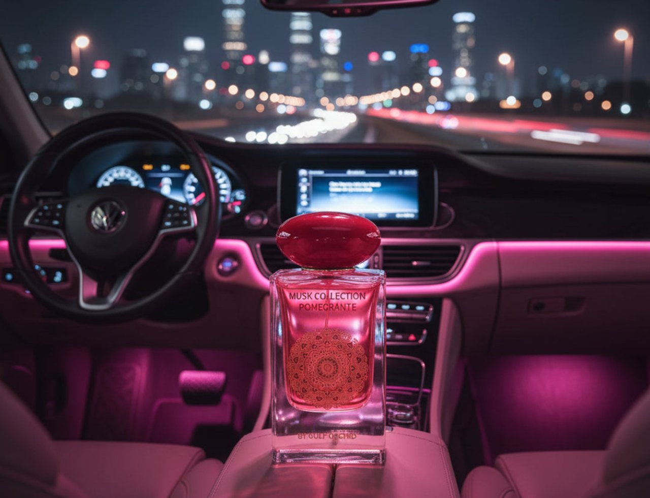 Gulf Orchid Pomegranate Musk 60ml Untuk Wanita — Botol minyak wangi bertutup merah dipamerkan di konsol tengah kereta pada waktu malam dengan lampu bandar di latar belakang