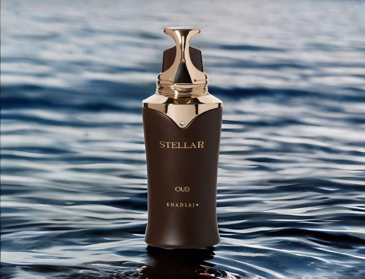 Khadlaj Stellar Oud by Khadlaj 100ml EDP Man — Brown bottle with gold accents and cap, floating on rippling blue water with a blurred sky background.