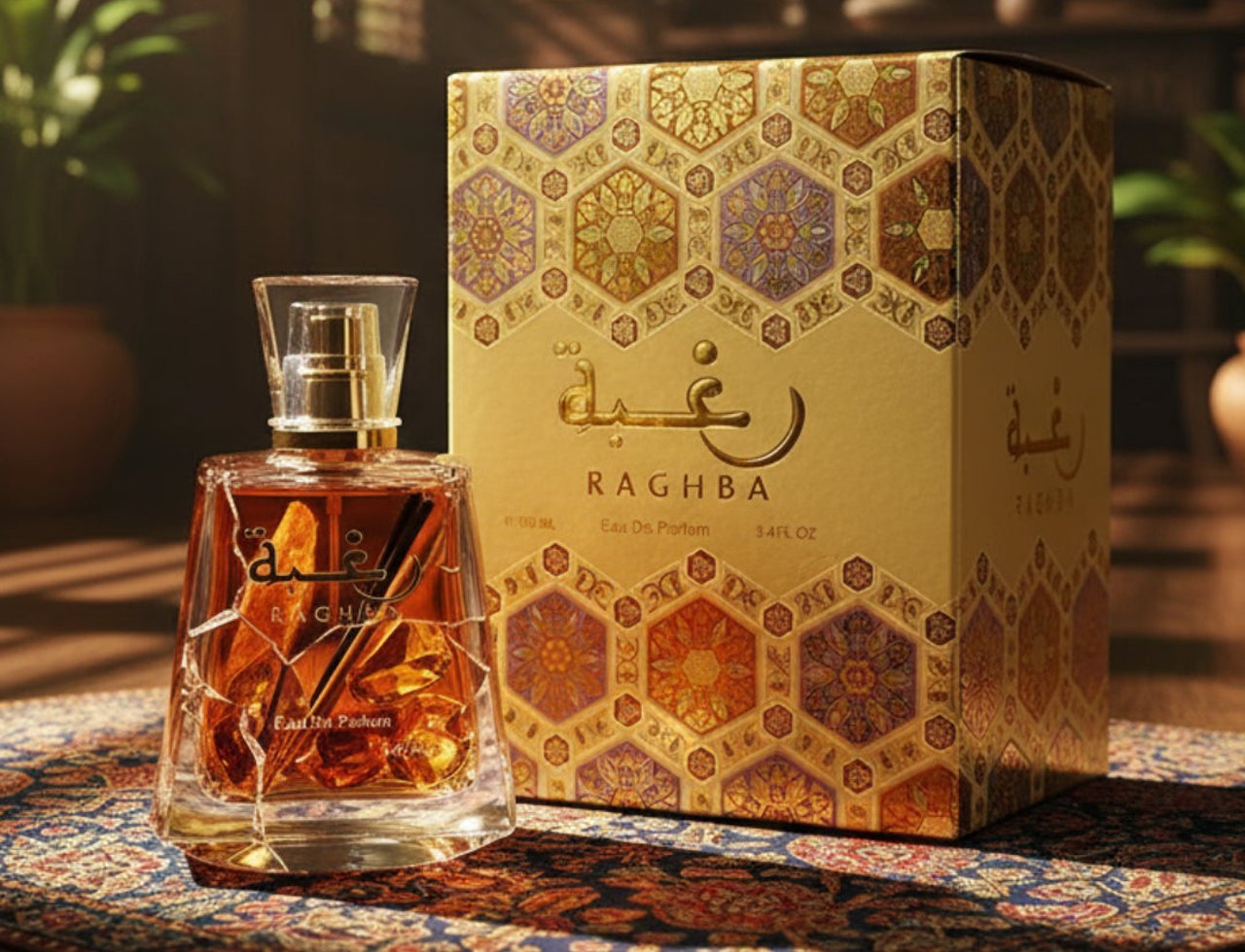 Lattafa Raghba by Lattafa 100ml EDP Unisex — Cecair ambar dalam botol kaca berfaset dengan penutup emas, bersebelahan kotak bermotif emasnya yang indah, diletakkan di atas permaidani bermotif.