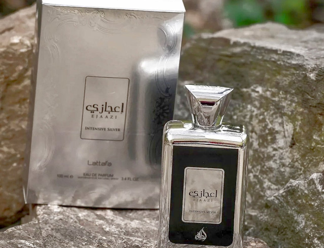 Lattafa Ejaazi Intensive by Lattafa – 100 ml Unisex, silver perfume bottle and box on textured rocks