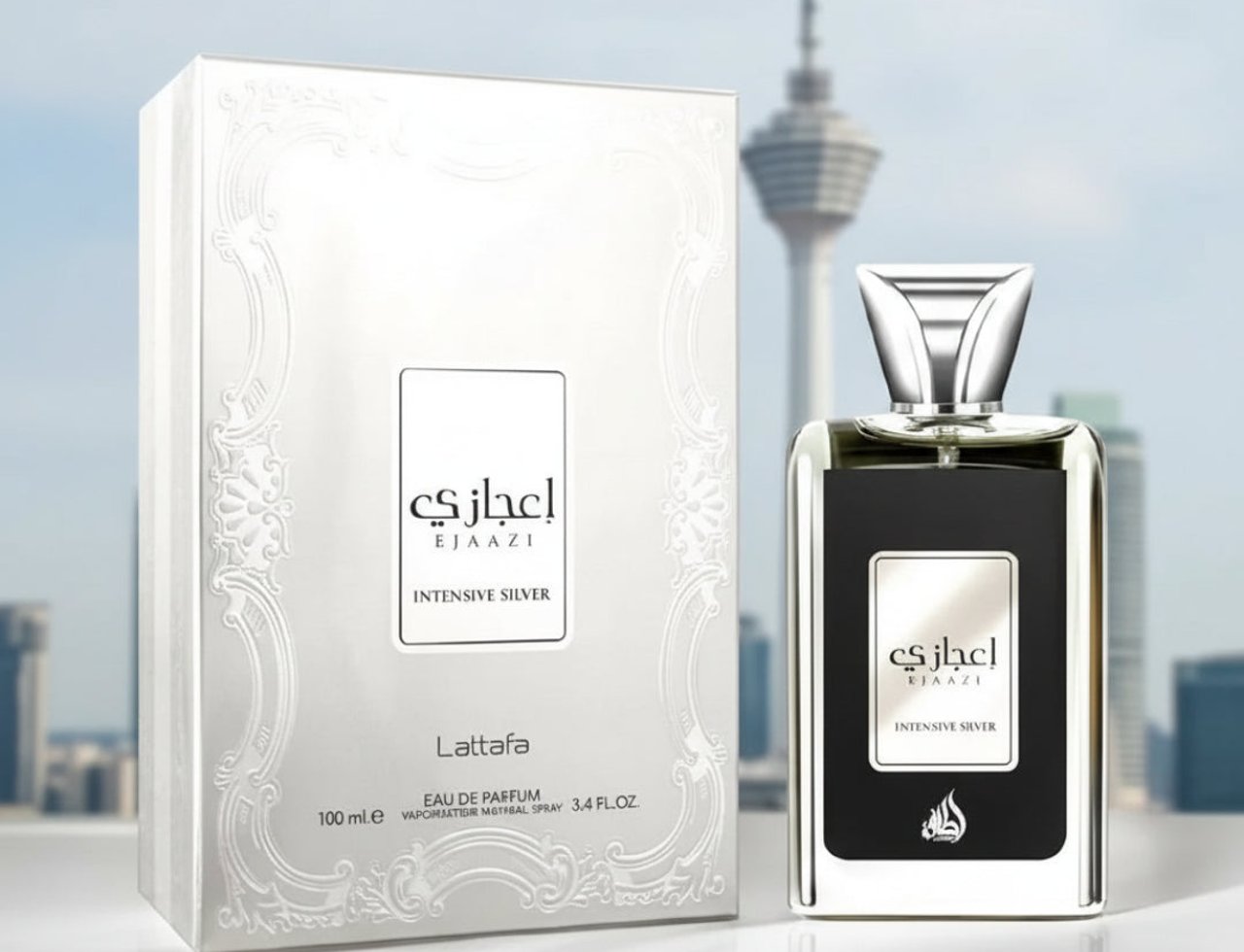 Lattafa Ejaazi Intensive by Lattafa – 100 ml Unisex, menampilkan kotak wangian putih berukir dan botol kaca jernih dengan cecair gelap, latar belakang bangunan pencakar langit