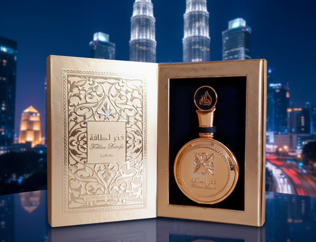 Lattafa Fakhar Extrait — Gold perfume bottle and ornate box displayed against a city skyline at night.