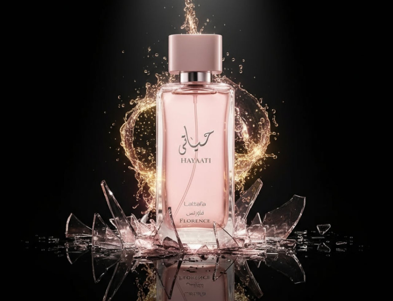 Lattafa Hayaati Florence by Lattafa 100ml EDP Women — Pink perfume bottle with gold splash effect and shattered glass fragments on a black background.