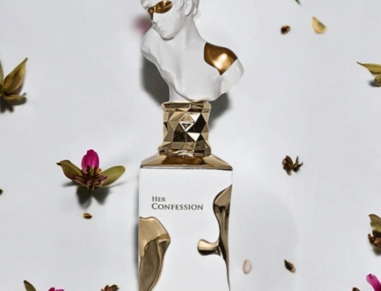 Lattafa Her Confession by Lattafa 100ml EDP — White perfume bottle with a bust of a woman as a cap, adorned with gold accents, surrounded by pink and green flowers and dried seed pods on a white background.