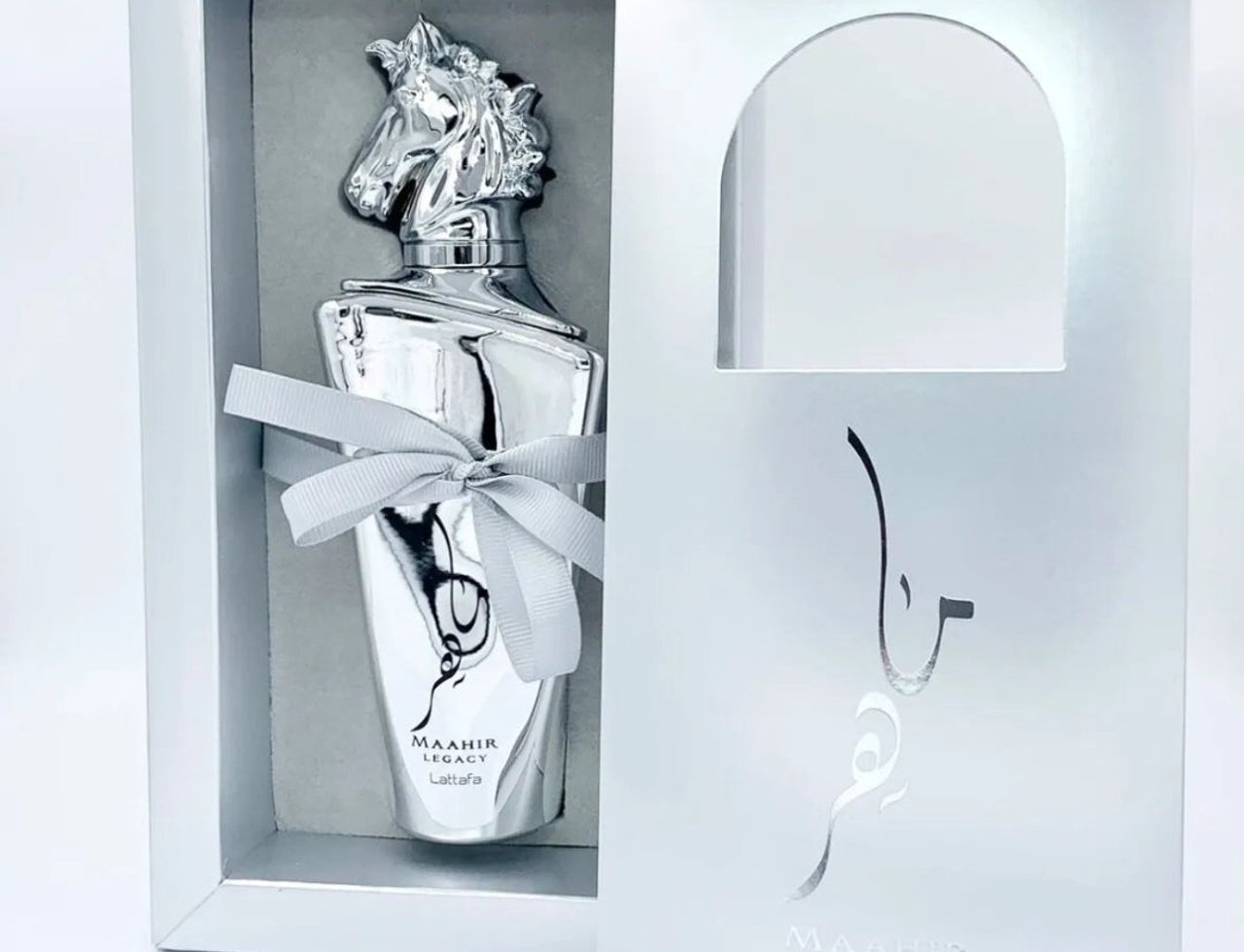 Lattafa Maahir Legacy by Lattafa 100ml EDP Man — Botol minyak wangi perak berkepala kuda, diikat reben kelabu, dalam kotak perak, dengan bungkusan luar terbuka.