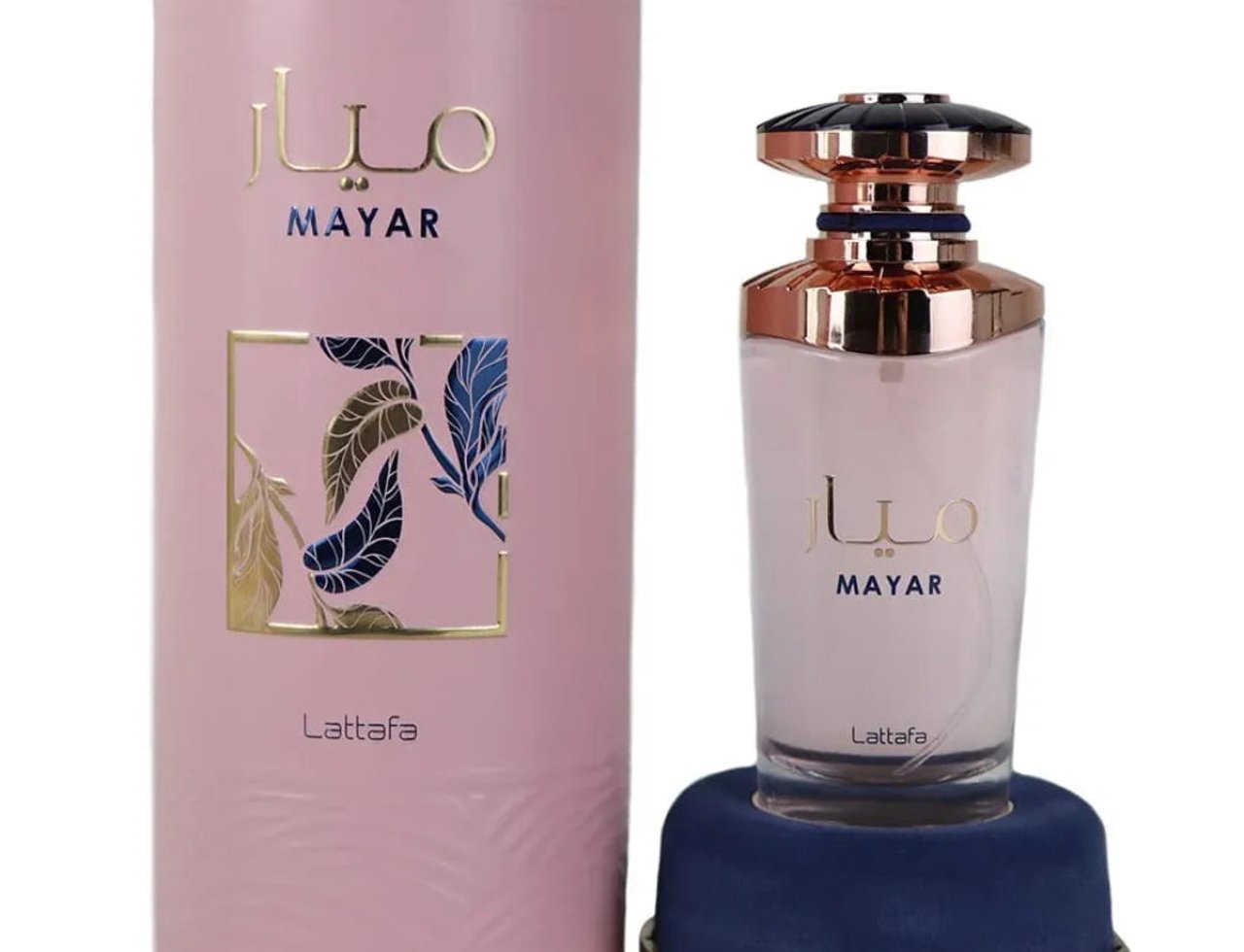 Lattafa Mayar by Lattafa EDP 100ml Woman — Kotak silinder merah jambu dengan aksen emas dan rekaan bunga bersebelahan botol minyak wangi kaca bertutup emas ros di atas tapak baldu biru.