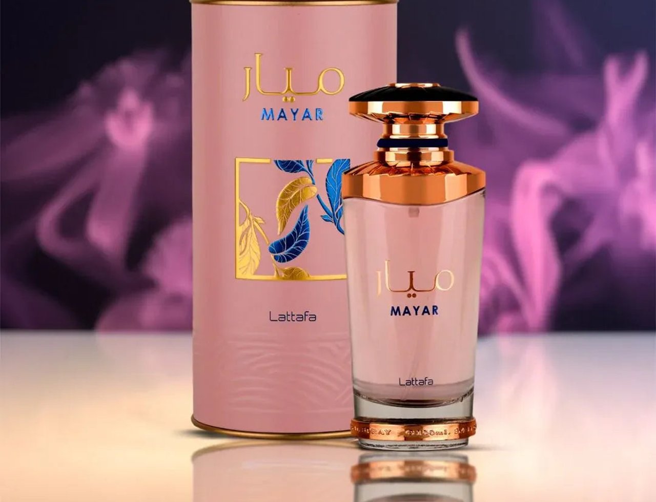 Lattafa Mayar by Lattafa EDP 100ml Woman — Pink cylindrical box and a pink glass perfume bottle with gold accents, set against a blurred purple and pink smoky background.