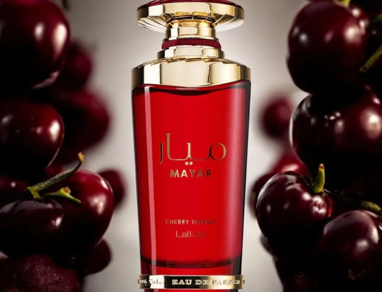 Lattafa Mayar Cherry Intense — Red glass perfume bottle with gold accents, surrounded by fresh cherries against a soft grey background.