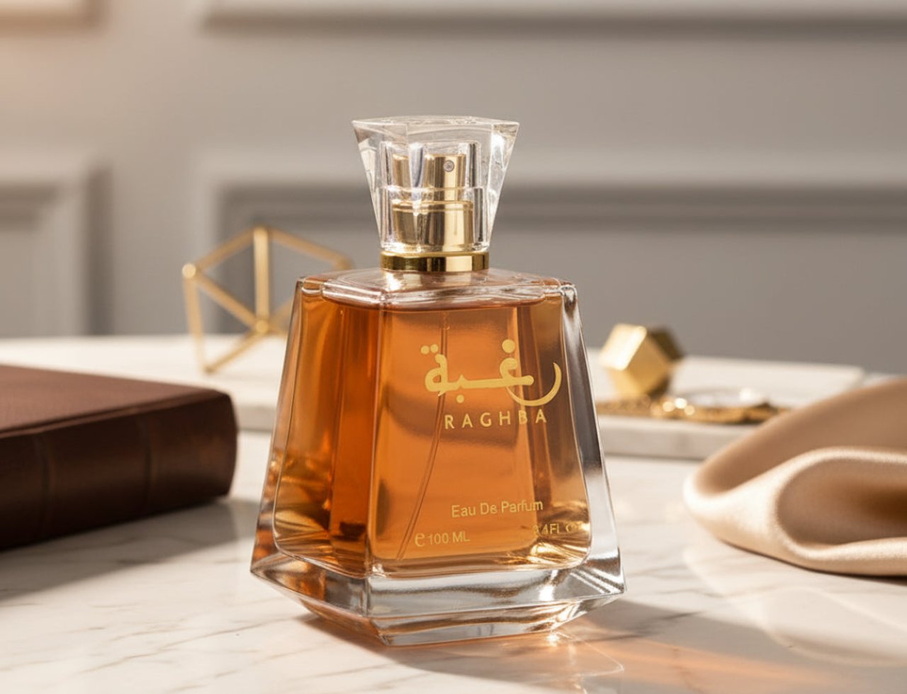 Lattafa Raghba by Lattafa 100ml EDP Unisex — Amber liquid in a faceted glass bottle with a clear faceted cap and gold accents, placed on a marble surface with a brown book and gold geometric decor.