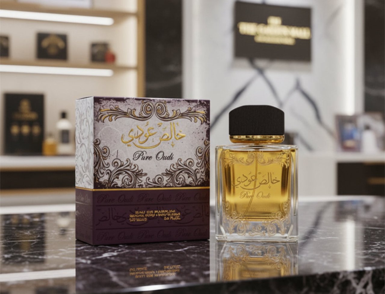Lattafa Khalis Pure Oudi by Lattafa EDP 100ml — Botol minyak wangi kaca jernih dengan perincian emas dan penutup hitam terletak di atas permukaan marmar bersebelahan kotak berhiasnya.