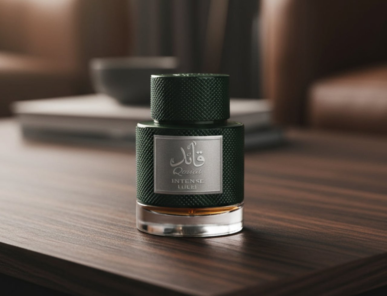 Lattafa Qaaed Intense by Lattafa 100ml EDP — A dark green textured perfume bottle with a silver label featuring Arabic calligraphy and English text, placed on a wooden table with a blurred background of furniture and a bowl.