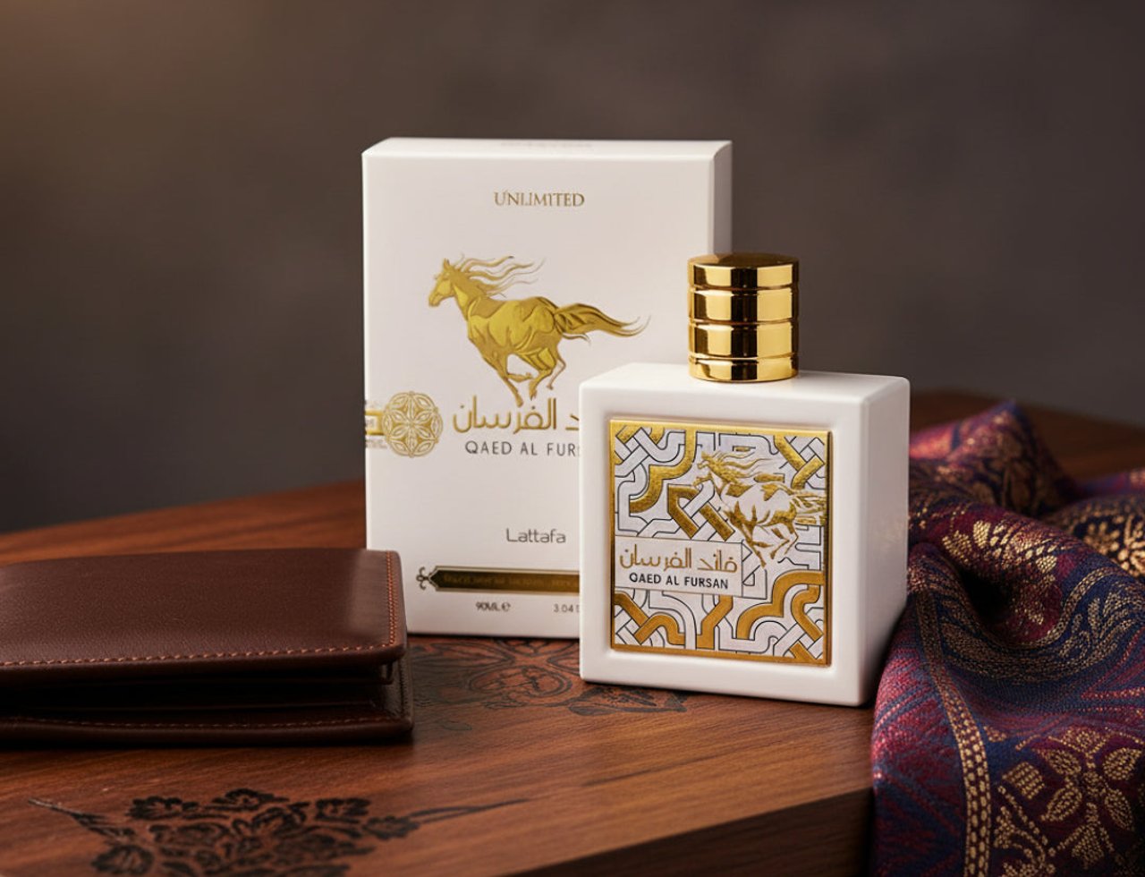 Lattafa Qaed Al Fursan Unlimited by Lattafa 90ml EDP — White perfume bottle with gold cap and ornate gold and white label, next to its white box with a gold horse illustration, on a wooden surface with a brown wallet and patterned fabric.