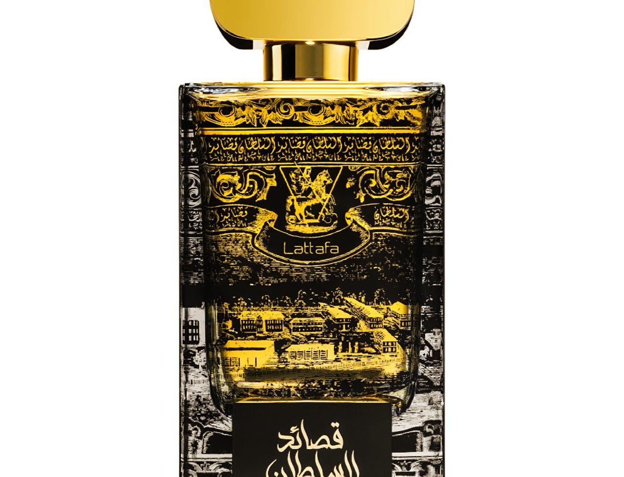 Lattafa Qasaed Al Sultan — A clear, front-facing shot of a rectangular glass perfume bottle with intricate gold Arabic calligraphy and a landscape illustration, topped with a polished gold cap.