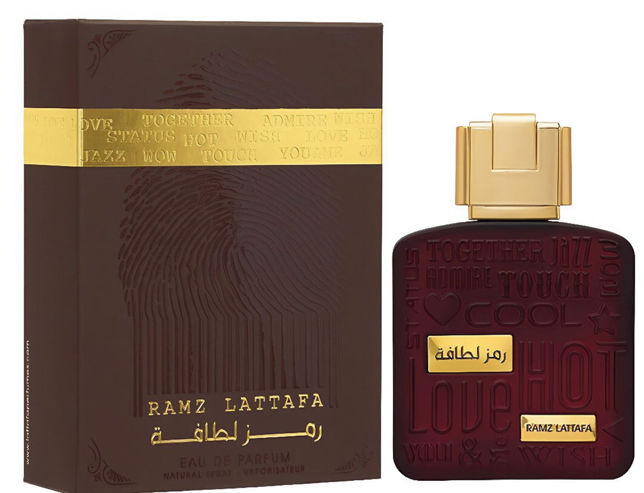Lattafa Ramz Gold Lattafa Woman 100ml EDP — Brown box with gold text and fingerprint design next to a dark red perfume bottle with gold cap and embossed text.