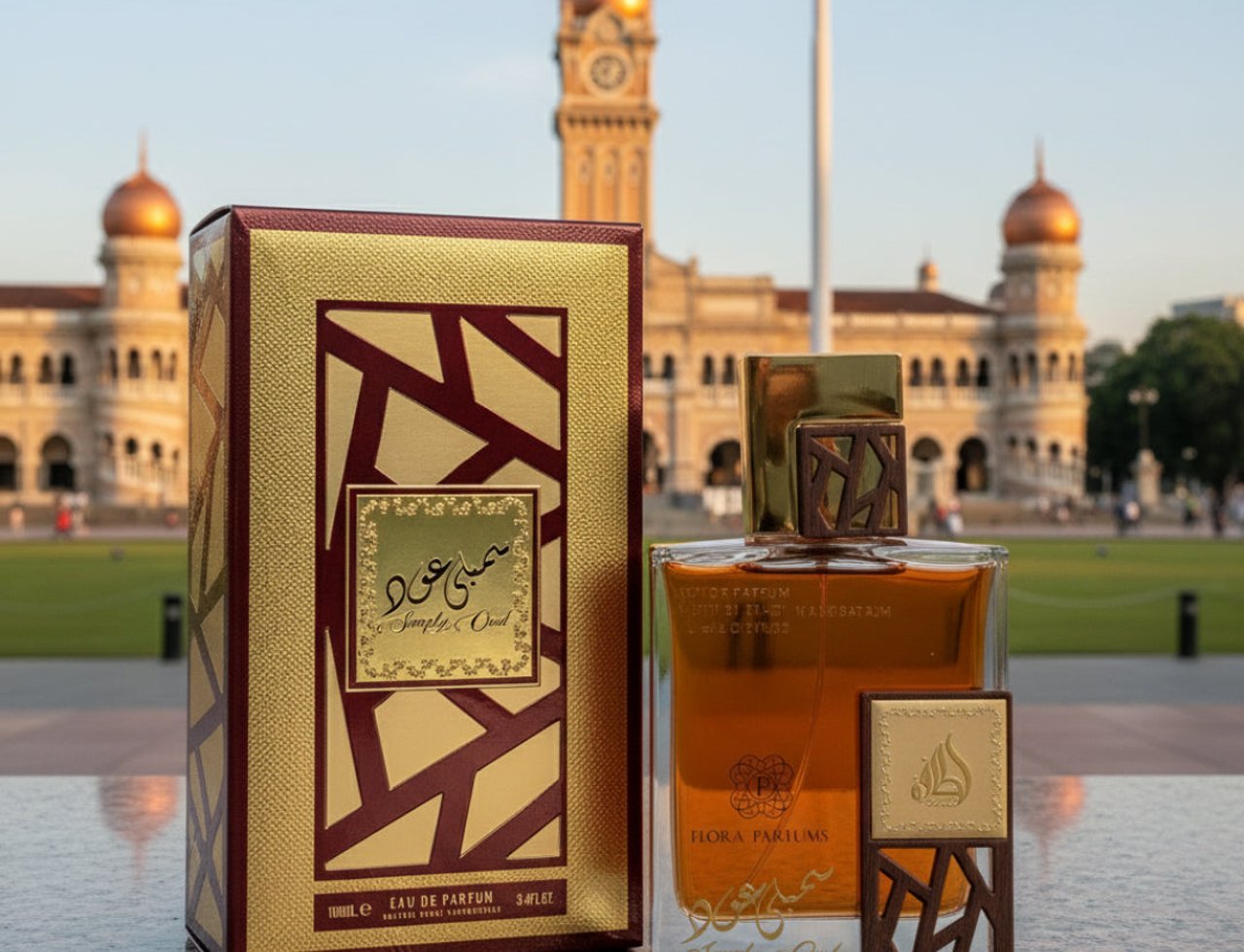 Lattafa Simply Oud by Lattafa 100ml EDP untuk Lelaki — Kotak corak emas dan merah maroon serta botol minyak wangi kaca jernih dengan aksesori penutup kayu, diletakkan di atas permukaan marmar dengan bangunan megah dan menara jam di latar belakang.