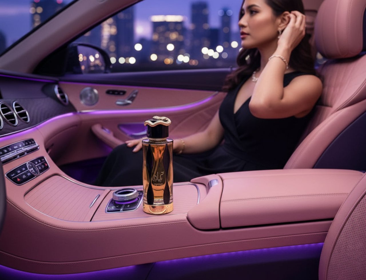 Lattafa Teriaq Intense by Lattafa 100ml Eau de Parfum — Wanita berbaju hitam duduk dalam kereta mewah dengan interior merah jambu, botol minyak wangi di konsol tengah, lampu bandar di latar belakang.