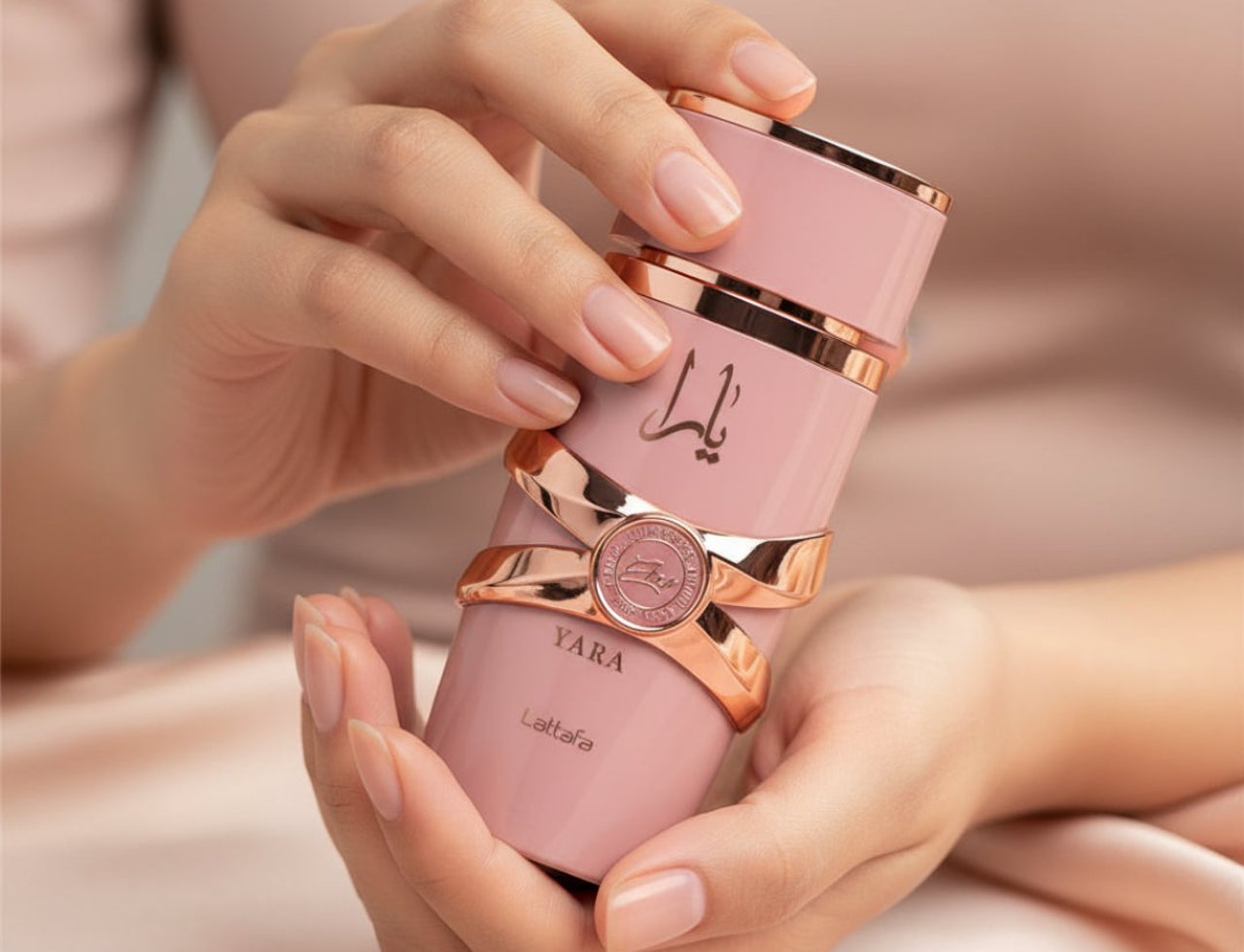 Lattafa Yara Elixir by Lattafa 100ml EDP — Botol minyak wangi merah jambu dengan perincian emas ros dan tulisan Arab, dipegang oleh tangan berserta kuku yang terjaga.