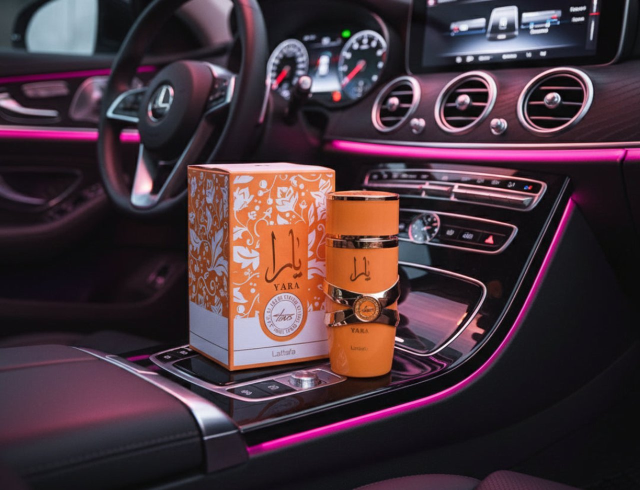 Lattafa Yara Tous by Lattafa 100ml EDP Women — Botol dan kotak minyak wangi oren dipamerkan di konsol tengah kereta mewah dengan pencahayaan ambien merah jambu.
