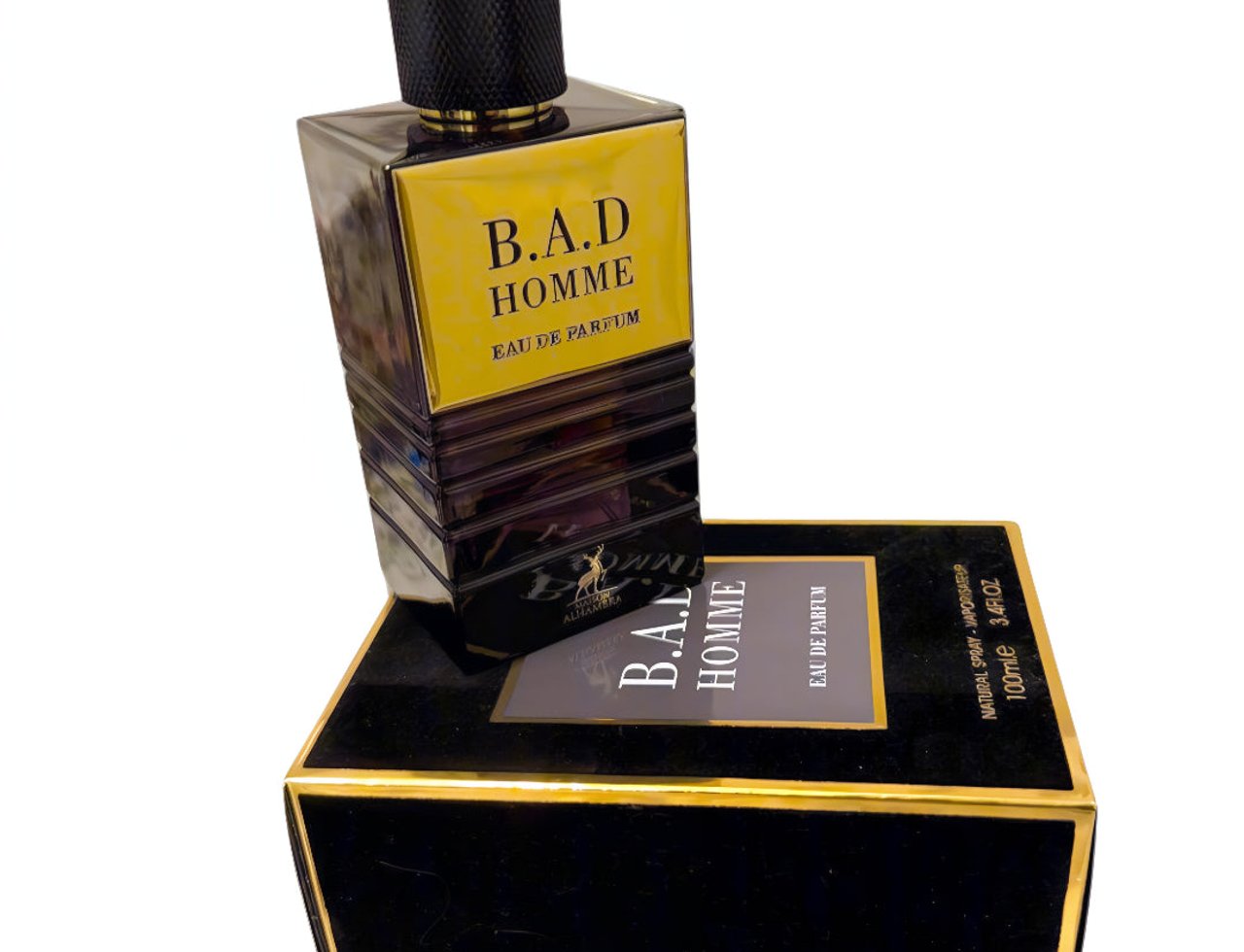 Maison Alhambra B.A.D. Homme Eau de Parfum — A black and gold perfume bottle with a textured black cap and gold accents, placed on its matching black velvet box with gold trim.