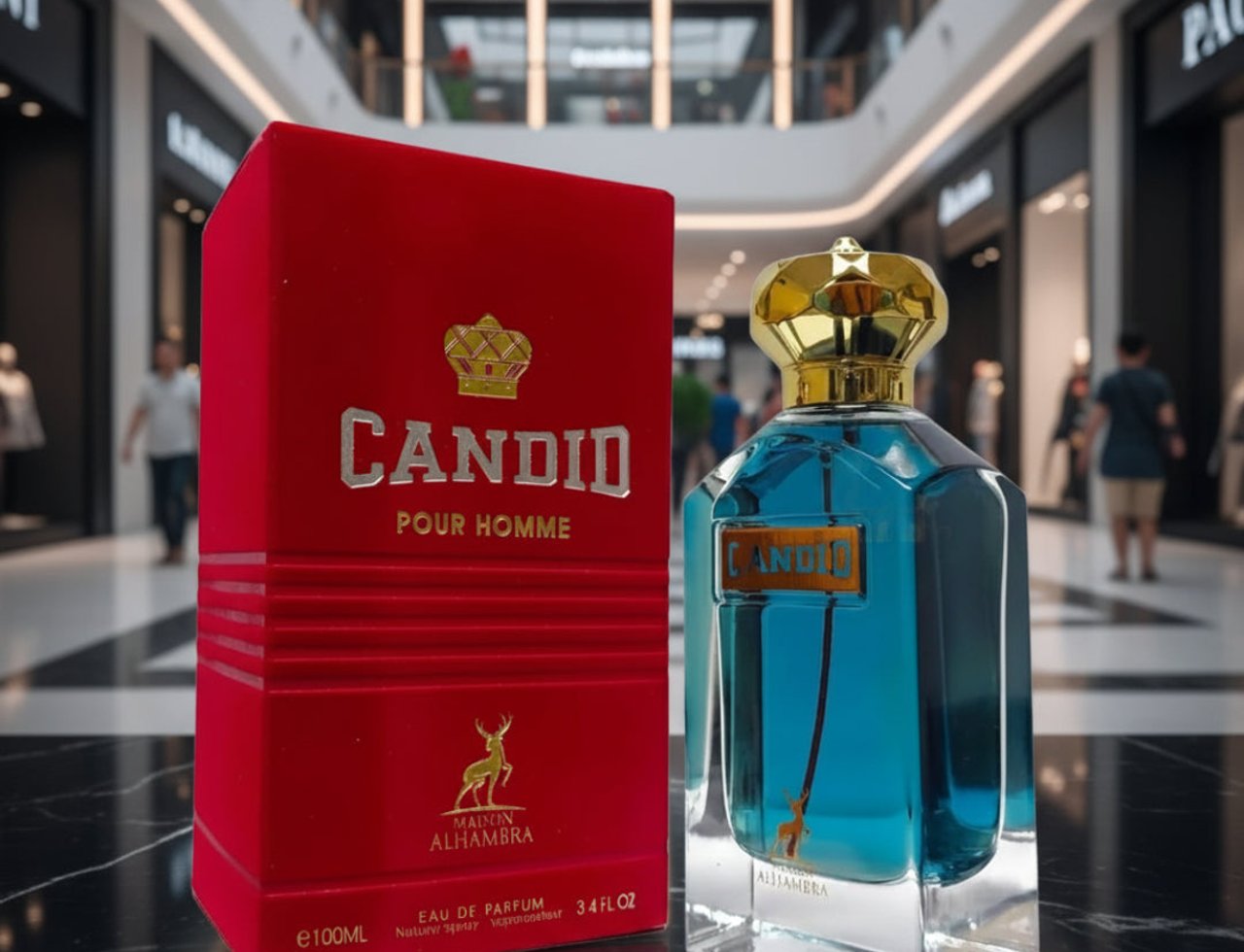 Maison Alhambra Candid Pour Homme — Kotak baldu merah dan botol kaca biru berpenutup emas, berlatar belakang pusat membeli-belah yang kabur.