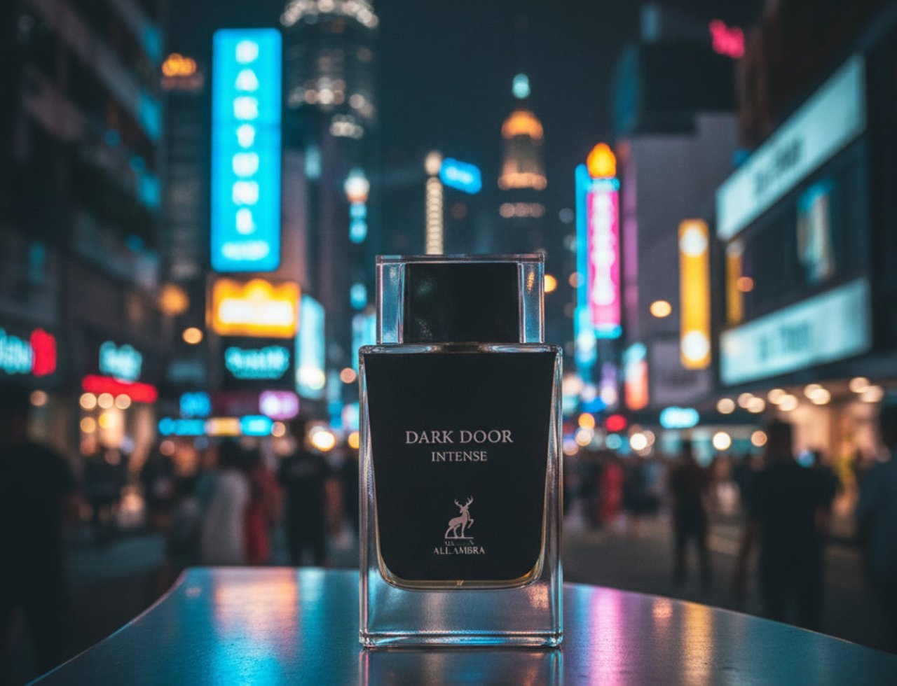 Maison Alhambra Dark Door Intense by Maison Alhambra — A clear glass perfume bottle with a dark liquid and black cap, labeled 'DARK DOOR INTENSE' and a deer logo, sits on a reflective surface against a blurred, neon-lit city street at night.