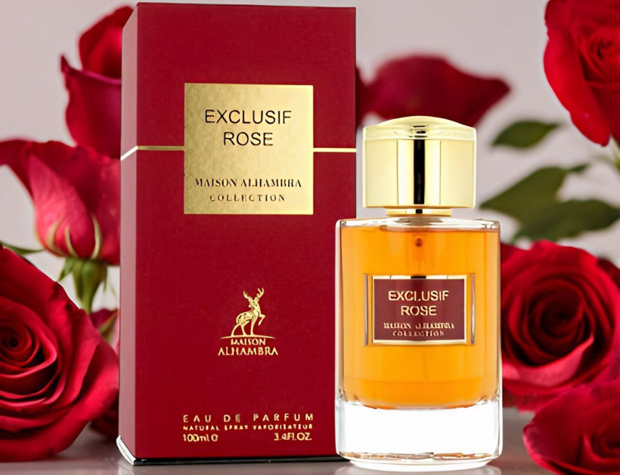 Maison Alhambra Exclusif Rose — Kotak merah dan botol minyak wangi berpenutup emas dengan bunga ros merah di latar belakang.