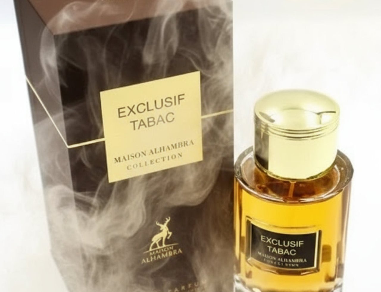 Maison Alhambra Exclusif Tabac — Kotak coklat dengan kesan asap dan label emas, bersebelahan botol minyak wangi kaca jernih dengan penutup emas dan label hitam.