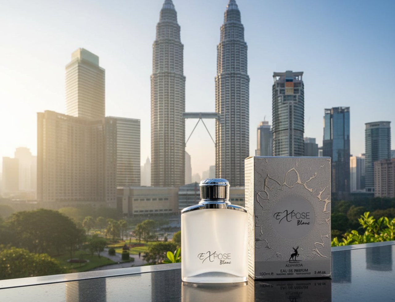 Maison Alhambra Expose Blanc by Maison Alhambra 100ml EDP Men — Botol minyak wangi kaca beku dan kotak corak peraknya diletakkan di atas permukaan reflektif dengan latar belakang Menara Berkembar Petronas.